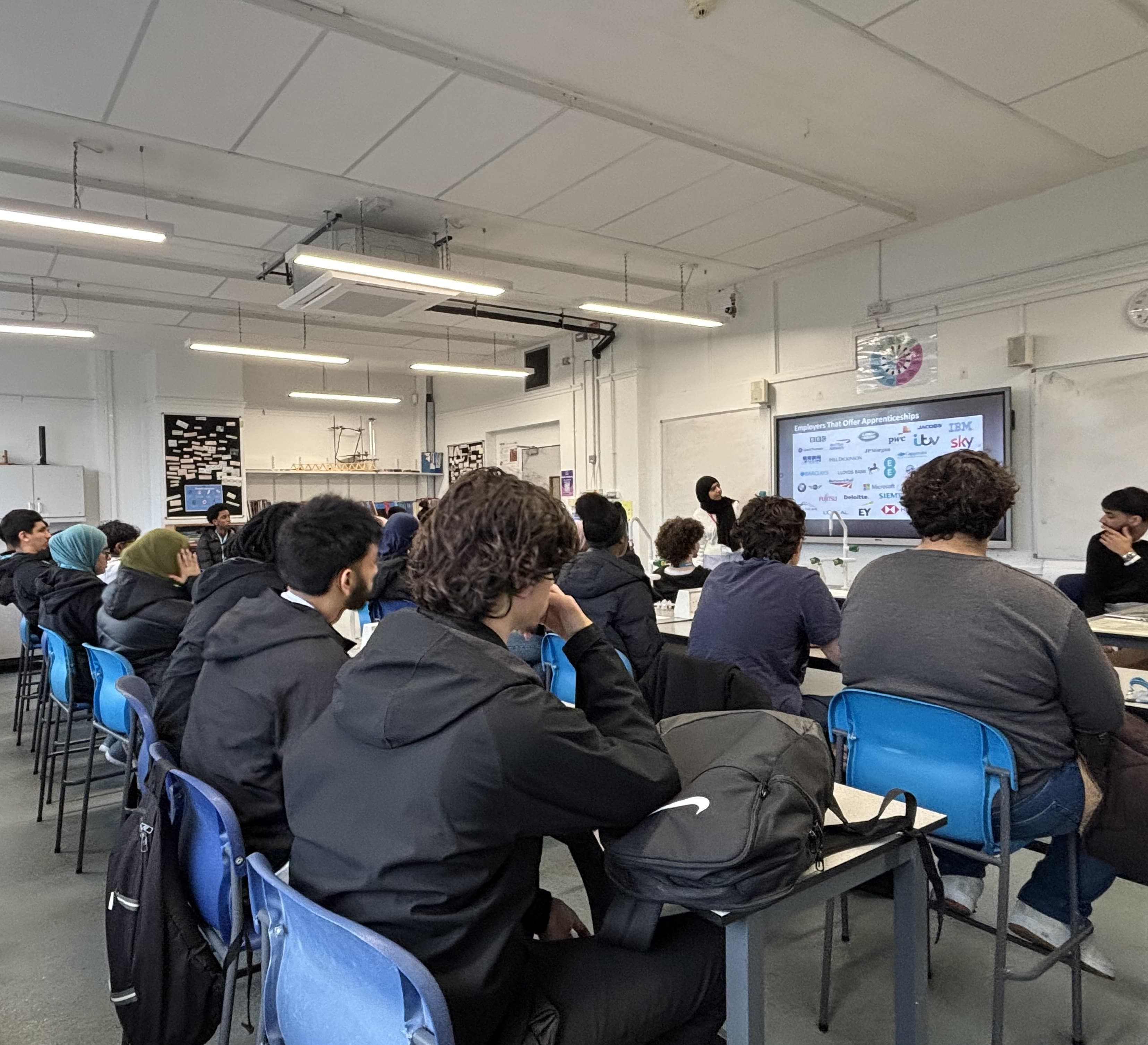LACE Network delivering an apprenticeship workshop in a school classroom, with a screen showing employers that offer apprenticeships including the BBC, IBM, PwC, and Sky